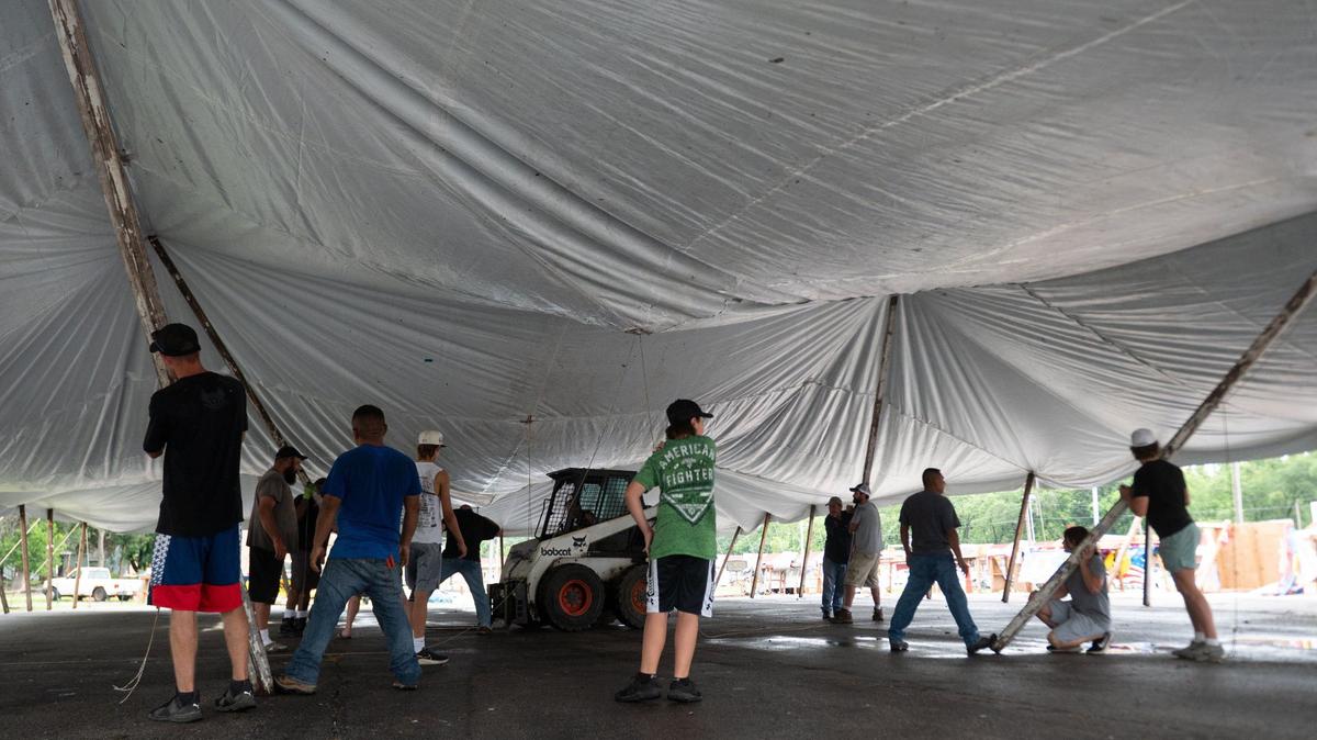 Friends and family of Stephanie and Kurt Eckard, owners of Dishonest Don’s Fireworks, place poles under a new tent Wednesday, after the original tent collapsed due to high winds Tuesday night in Riverside.