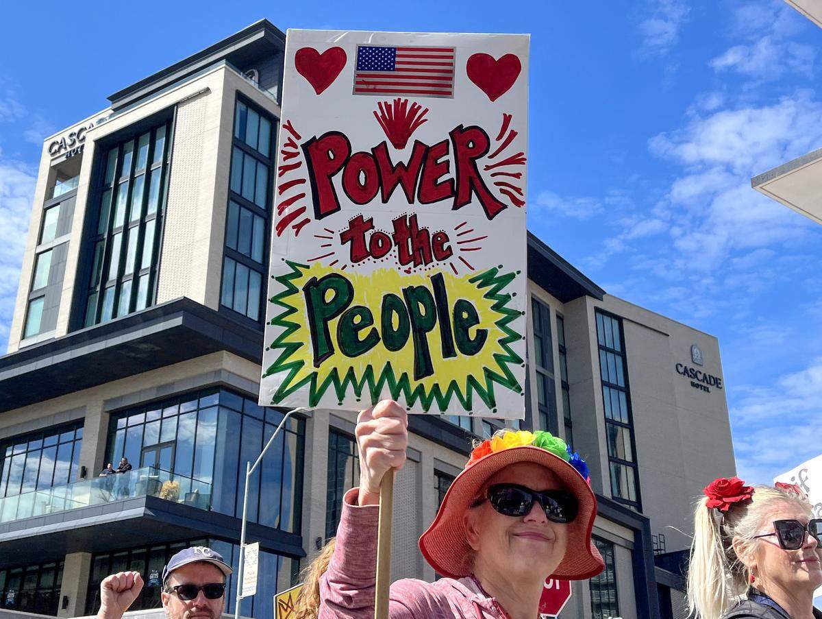 A protester holds up a sign while marching along Broadway Boulevard in Kansas City on Saturday, March 28, 2026, during a No Kings protest against the Trump administration.