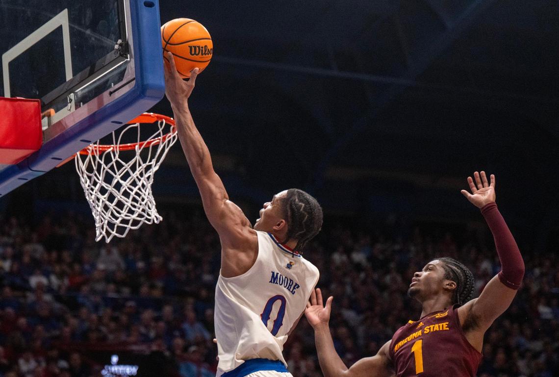 Kansas Jayhawks guard Shakeel Moore (No. 0) scores past the defense of Arizona State Sun Devils guard Alston Mason during a college basketball game at Allen Fieldhouse in Lawrence, Kansas, on Wednesday, Jan. 8, 2025.