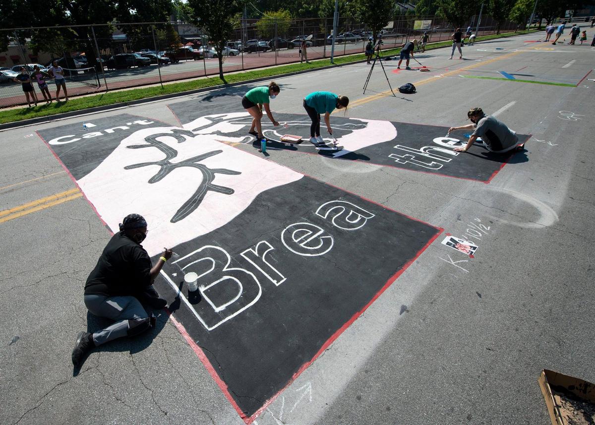 Greer Cooper-Dosrey, left, helped outline the letters for the message “I can’t breathe” inside the giant “K” that is part of the Black Lives Matter mural painted Saturday on Brookside Blvd. near 63rd St.