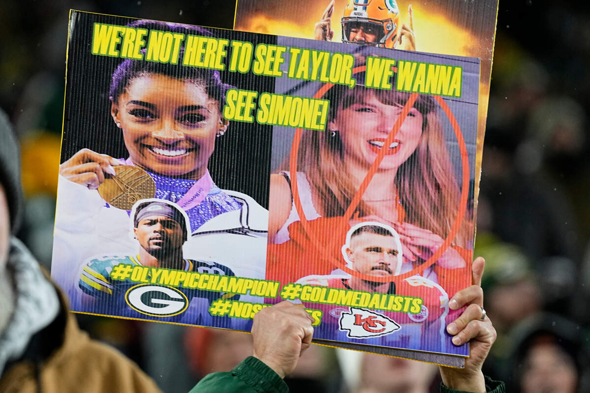 A fan holds up a sign referencing both gymnast Simone Biles and singer Taylor Swift prior to the game between the Kansas City Chiefs and Green Bay Packers at Lambeau Field.