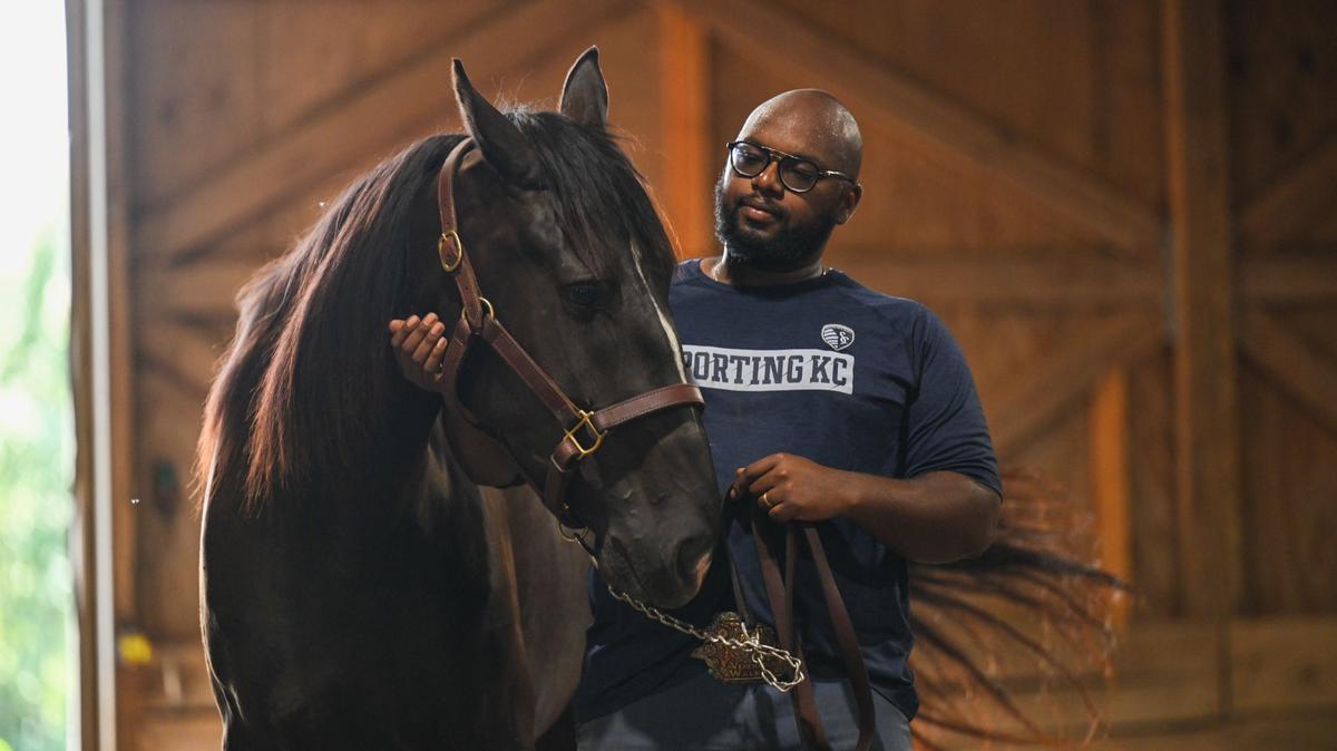 Trae Q. L. Venerable stands in barn with his show horse, Stormy. Venerable comes from a family of Black cowboys who have been ranchers for decades.