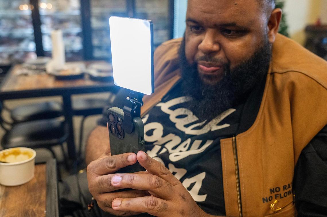 Glenn Robinson records a food review video using his mobile device and a studio light setup.