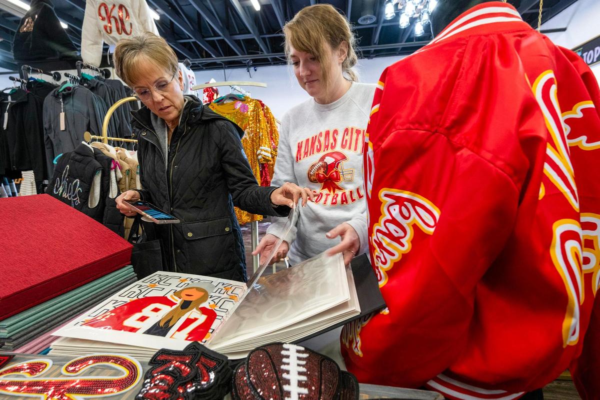 Fran Douthat, left, of Mission Hills, looks over a book of direct to film transfers and talks with Stephanie Ault, an employee at Maxi Laine’s Boutique. Douthat was looking for Chiefs and college themed patches for letter-style jackets she was customizing.