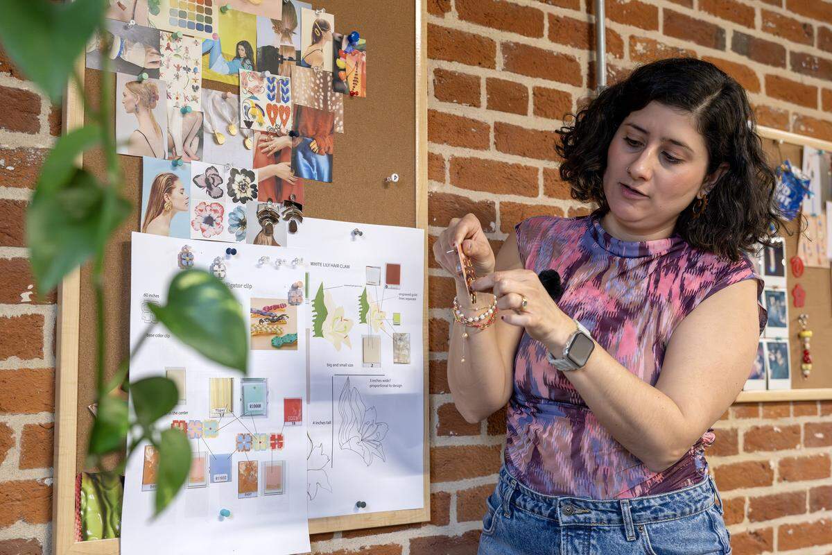 Paulina Otero discusses a design board while showing a pair of earrings during a tour of her studio on Tuesday, March 3, 2026, in Kansas City.