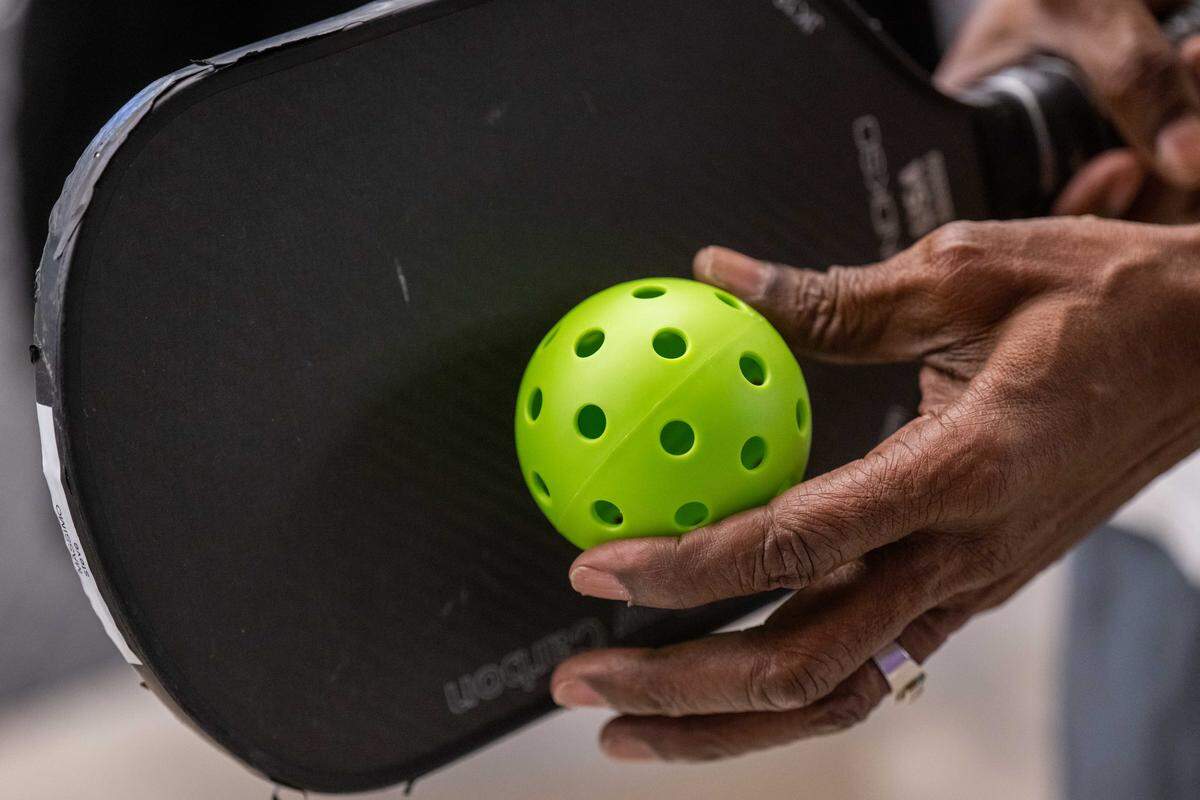 Steve Bowie holds a ball and a paddle during a meeting of the Black Pickleball Club at SW19 at the Stadium, on Sunday, Feb. 22, in Kansas City. The game is played with a paddle — an oversized version of a ping pong paddle — and a wiffle ball. It resembles a mix of tennis and ping pong.