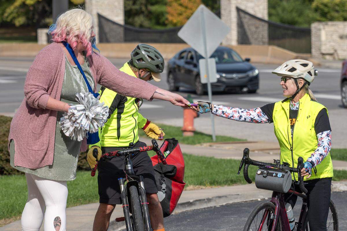 A bicyclist stops to receive candy from a Russell Stover employee while passing through the company's headquarters during the annual Halloween giveaway on Friday, Oct. 31, 2025, in Kansas City.