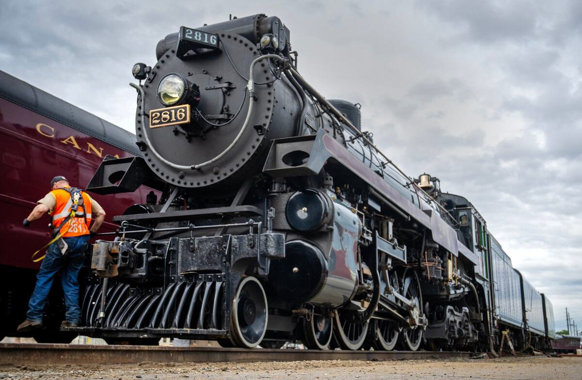 Ben Cummings, a locomotive engineer from Lethbridge, Alberta, Canada, hops off the Empress 2816, a 1930 steam locomotive while doing some maintenance on Thursday, May 16, 2024, at the CPKC rail yard in Kansas City. Canadian Pacific Kansas City (CPKC) is celebrating its’ anniversary, the merger with KC Southern, with the Final Spike Anniversary Steam Tour, which makes a stop at Union Station on Saturday, May 18, 2024.