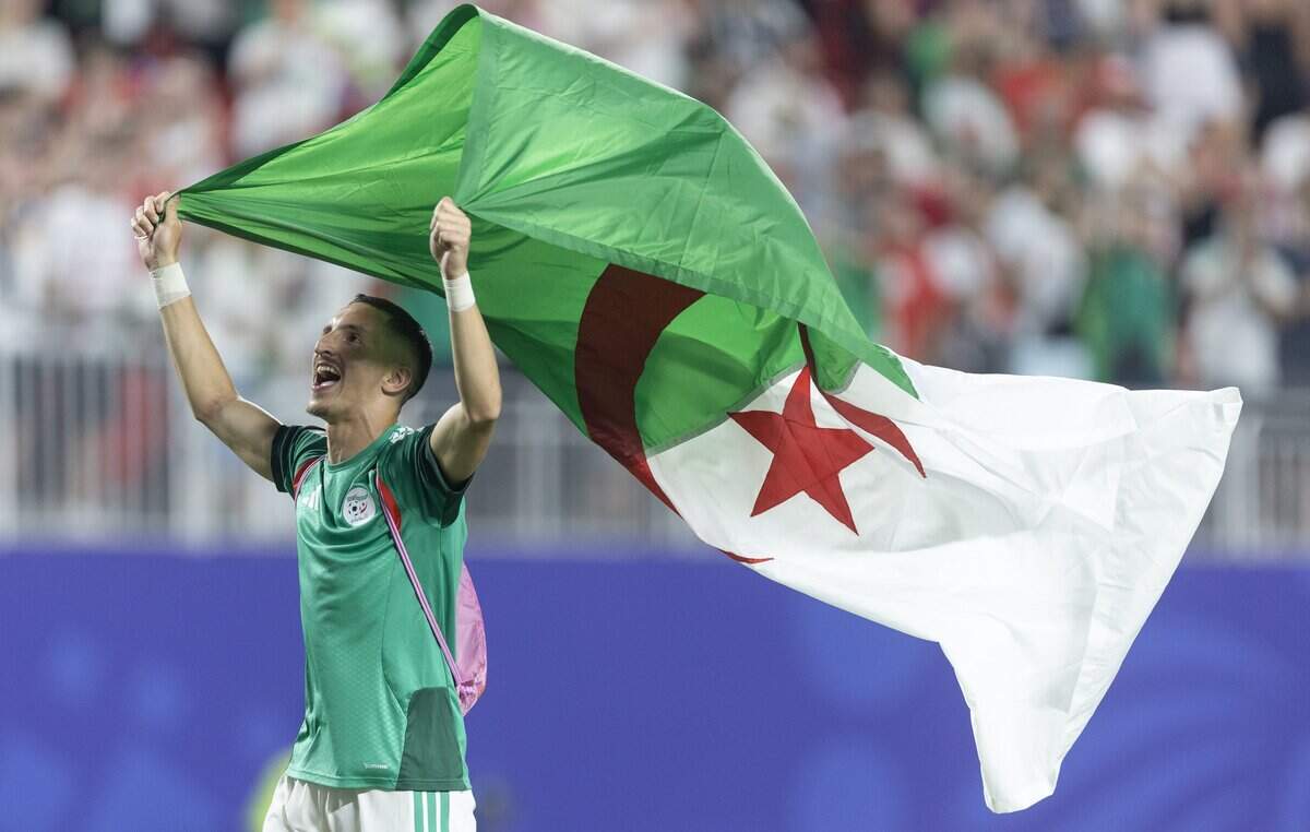 Algeria midfielder Adil Boulbina (20) waves his country's flag after a draw with Austria moved Algeria to the round of 32.