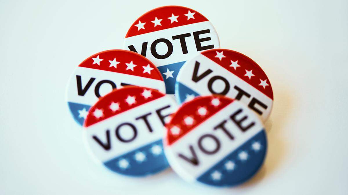 closeup of some vote badges for the United States election on an off-white background election voting primary ballot box