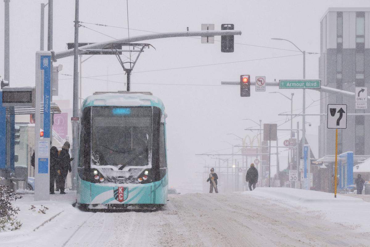 KC Streetcar riders run to the Armour Boulevard stop on Main Street as snow blanketed the Kansas City metro area on Monday, Dec. 1, 2025. The area is expected to accumulate 3 to 5 inches.