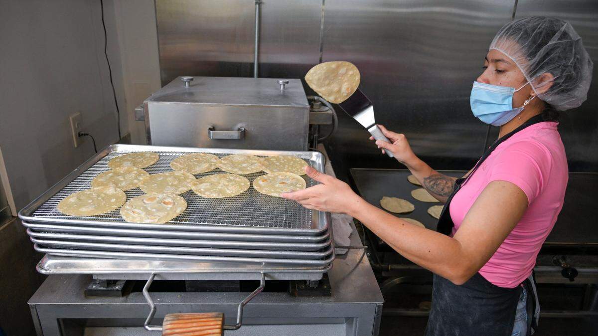 Diana Forero flips a tortilla onto a cooling rack before it’s packaged up and sent out to customers.