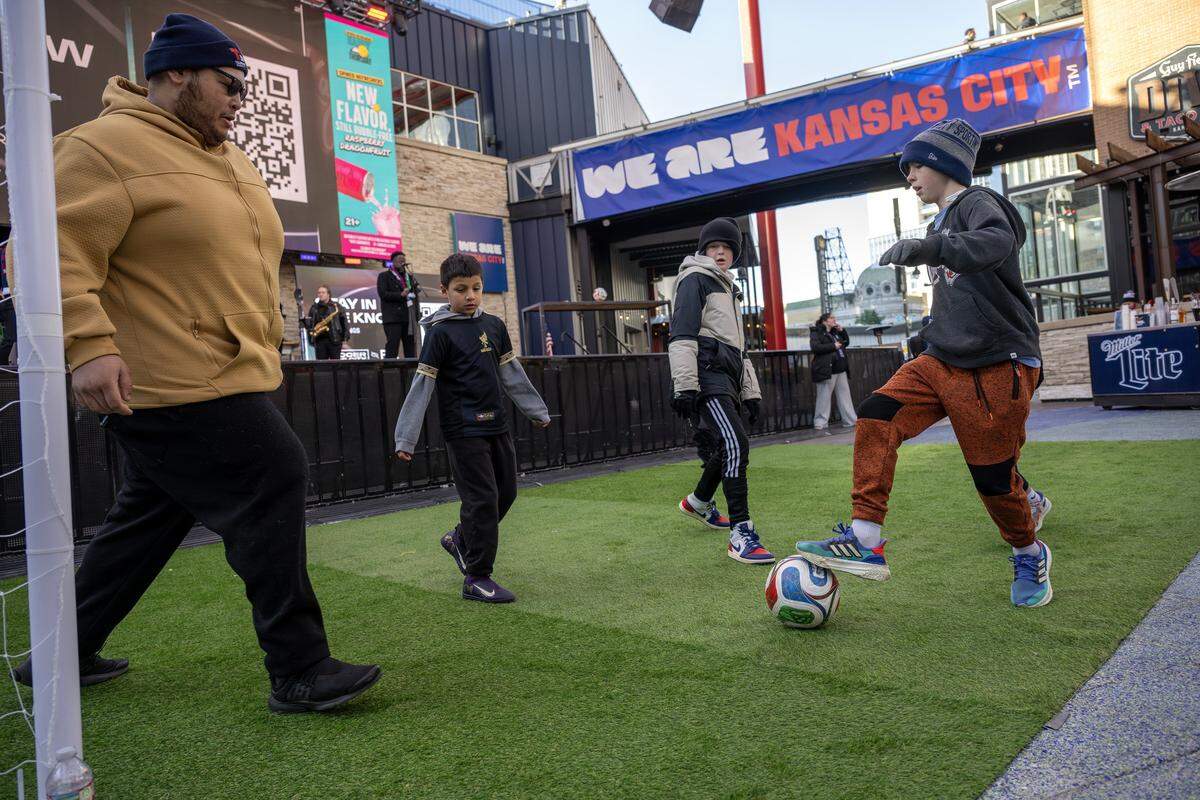 Children play on a mini pitch in front of the stage during the FIFA World Cup draw watch party at the Power & Light District on Friday, Dec. 5, 2025, in Kansas City,