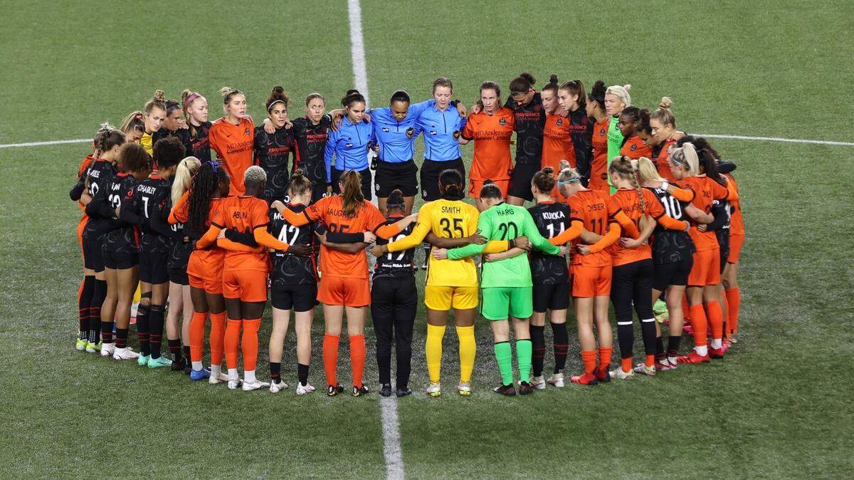 Portland Thorns and Houston Dash players, along with referees, gather at midfield, in demonstration of solidarity with two former NWSL players who came forward with allegations of sexual harassment and misconduct against a prominent coach, during the first half of an NWSL soccer match in Portland, Ore., Wednesday, Oct. 6, 2021. (AP Photo/Steve Dipaola)