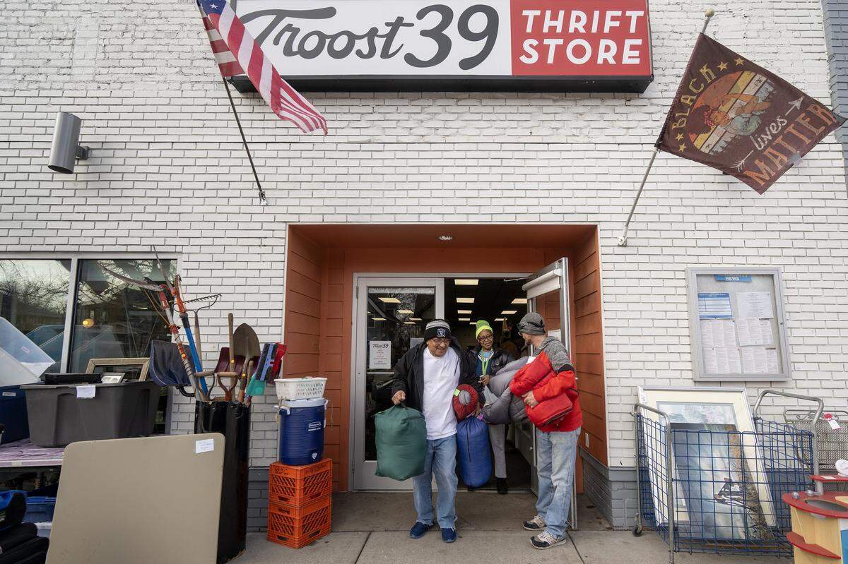 Employee Mario Vargas, left, and William Benjamin Singleton, right, a volunteer, carry sleeping to the car for customer Adrienne Williams, center, who purchased the items at Troost39 on Thursday, Jan. 22 2026, in Kansas City. Williams will provide unhoused individuals with the sleeping bags.