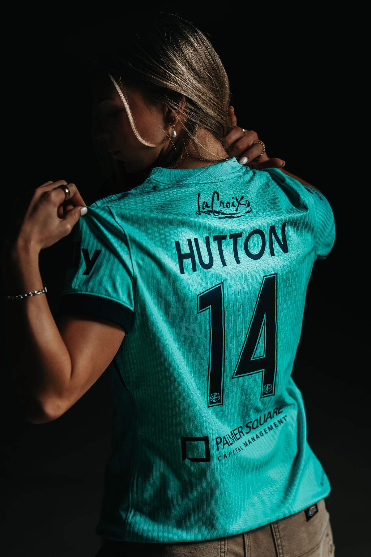 The Kansas City Current’s Claire Hutton shows off the back of the club’s new jersey for the 2025 season. The Current are sporting teal jerseys for the first time.