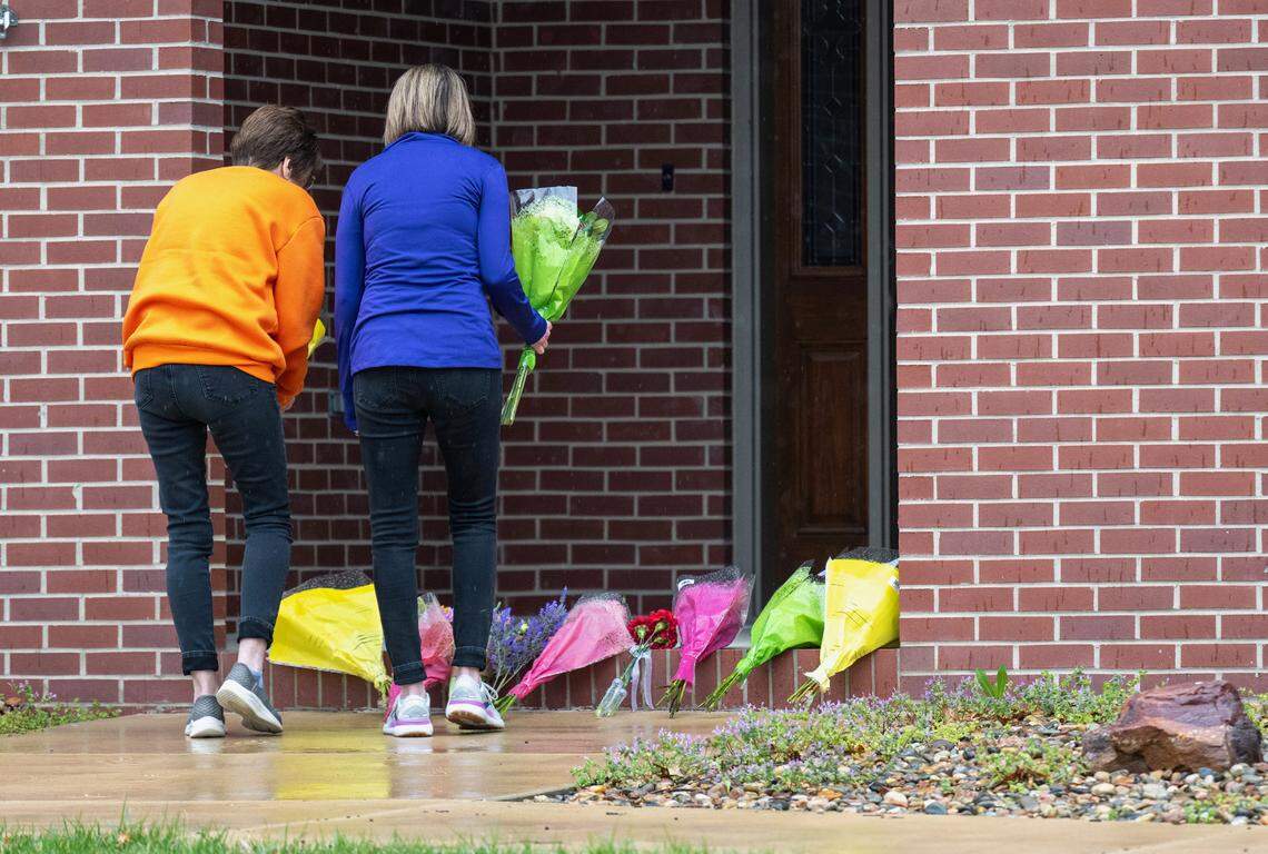 Two women leave flowers and pay tribute to the Rev. Arul Carasala, a Catholic priest, who was shot and killed Thursday, by a man near the parish rectory of Saints Peter and Paul Catholic Church in Seneca, Kansas.