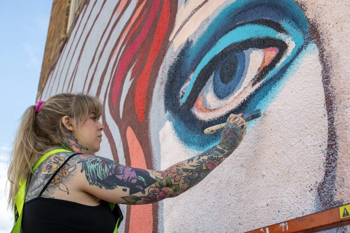 Artist Christine Riuzel paints eye details on a Chappell Roan mural along Broadway Boulevard on Wednesday, Sept. 24, 2025, in Kansas City.