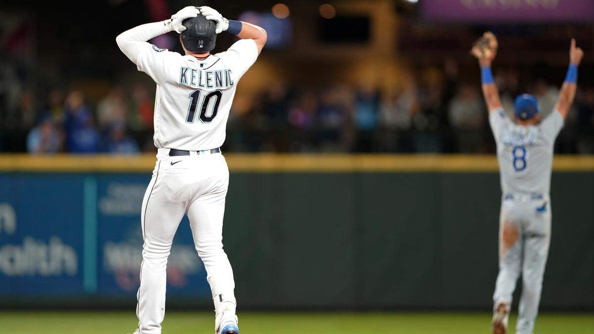 Seattle Mariners’ Jarred Kelenic (10) and Kansas City Royals shortstop Nicky Lopez (8) react after Royals left fielder Andrew Benintendi made a leaping catch at the wall of a ball hit by Kelenic during the eighth inning of a baseball game Thursday, Aug. 26, 2021, in Seattle.