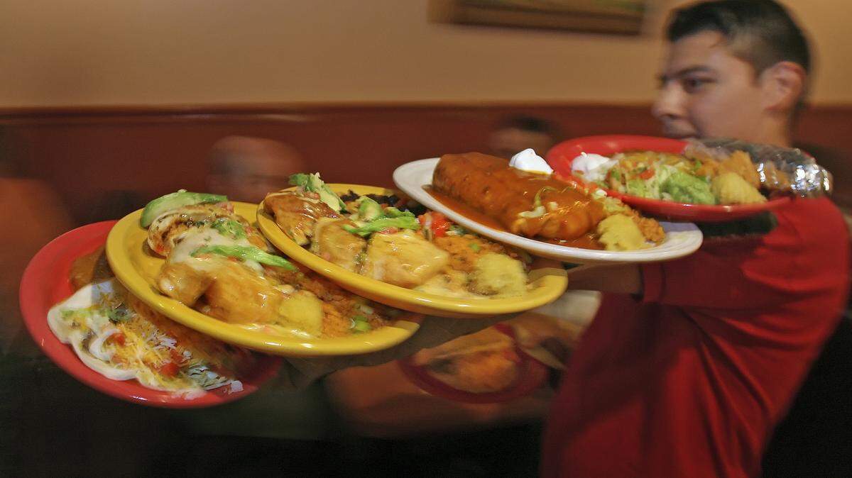 PHOTO BY: ALLISON LONG/THE KANSAS CITY STAR 081308_People enjoy their dinner at Mi Ranchito in downtown Overland Park on Wednesday, August 13th.  Waiter Alex Gomez carries plates of food during the busy dinner rush. One reader stated that this restaurant was one of the best for a date and hanging with friends.  Known for their food and potent margaritas.