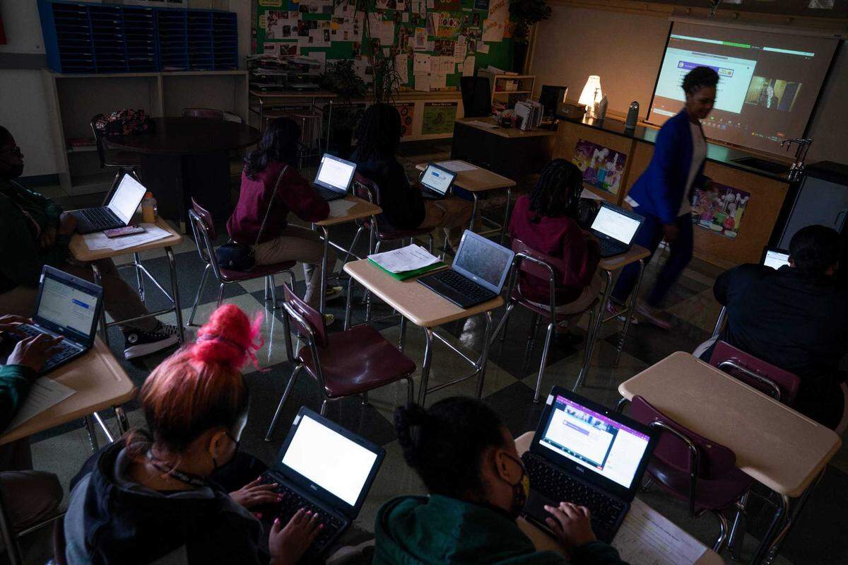 Samantha Koonce Gaines, the Thurgood Marshall Academy Public Charter High School Science Department chair and Biology teacher, helping students with questions and encouragement during the physics class taught virtually by physics instructor Rachel Pomeroy, on screen, on May 10, 2023.