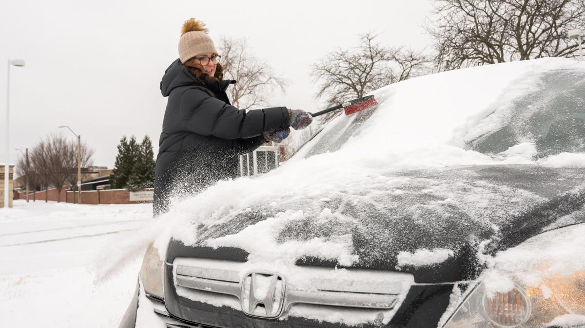 Kate Rezac, visiting from Omaha, brushes snow off her vehicle in Kansas City on Wednesday, Feb. 12, 2025. Kansas City was blanketed with snow overnight and into the early morning Wednesday.