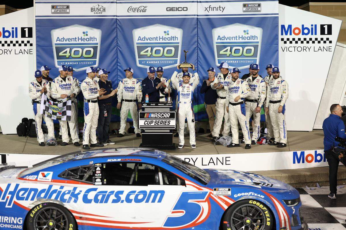 NASCAR Cup Series driver Kyle Larson celebrates with the trophy and his crew after winning Sunday’s weather-delayed AdventHealth 400 at the Kansas Speedway.