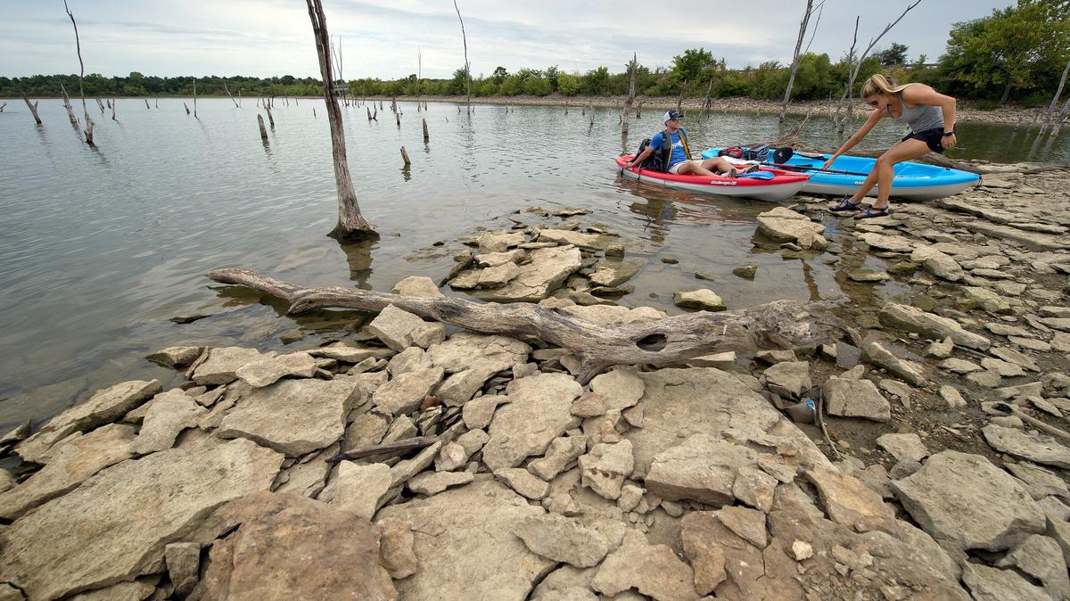 Kayakers Guy Vinson and Molly Hertz came ashore at Smithville lake on Wednesday, July 25, 2018, in an area normally under water this time of year. The U.S. Army Corps of Engineers is warning boaters to use caution because submerged hazards are now close to the surface due to drought conditions. The lake more than 2 feet below.