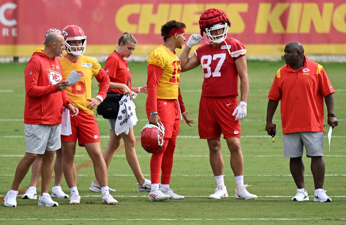 Chiefs quarterback Patrick Mahomes (15) talks with tight end Travis Kelce (87) as offensive coordinator Eric Bieniemy looked on during training camp on Friday, July 29, 2022 at Missouri Western State University, in St. Joseph, Missouri. Guard Vitaliy Gurman (76) was in on the play as wide receiver Skyy Moore (24) talked with head coach Andy Reid.