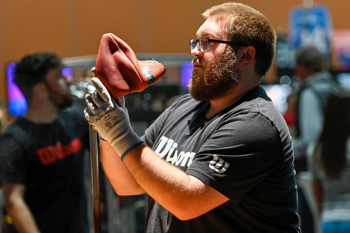 An employee works on a Wilson football at the NFL Super Bowl Experience on Friday, Feb. 10, 2023, at the Phoenix Convention Center.