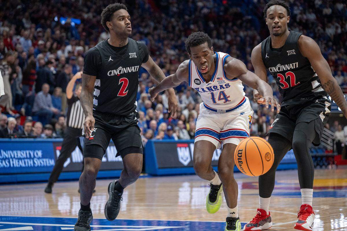 Kansas Jayhawks guard Melvin Council Jr. (14) goes for a loose ball as Cincinnati Bearcats guard Jizzle James (2) and Cincinnati Bearcats forward Jalen Celestine (32) defend in the second half Allen Fieldhouse on Saturday, Feb. 21, 2026, in Lawrence, Kansas.