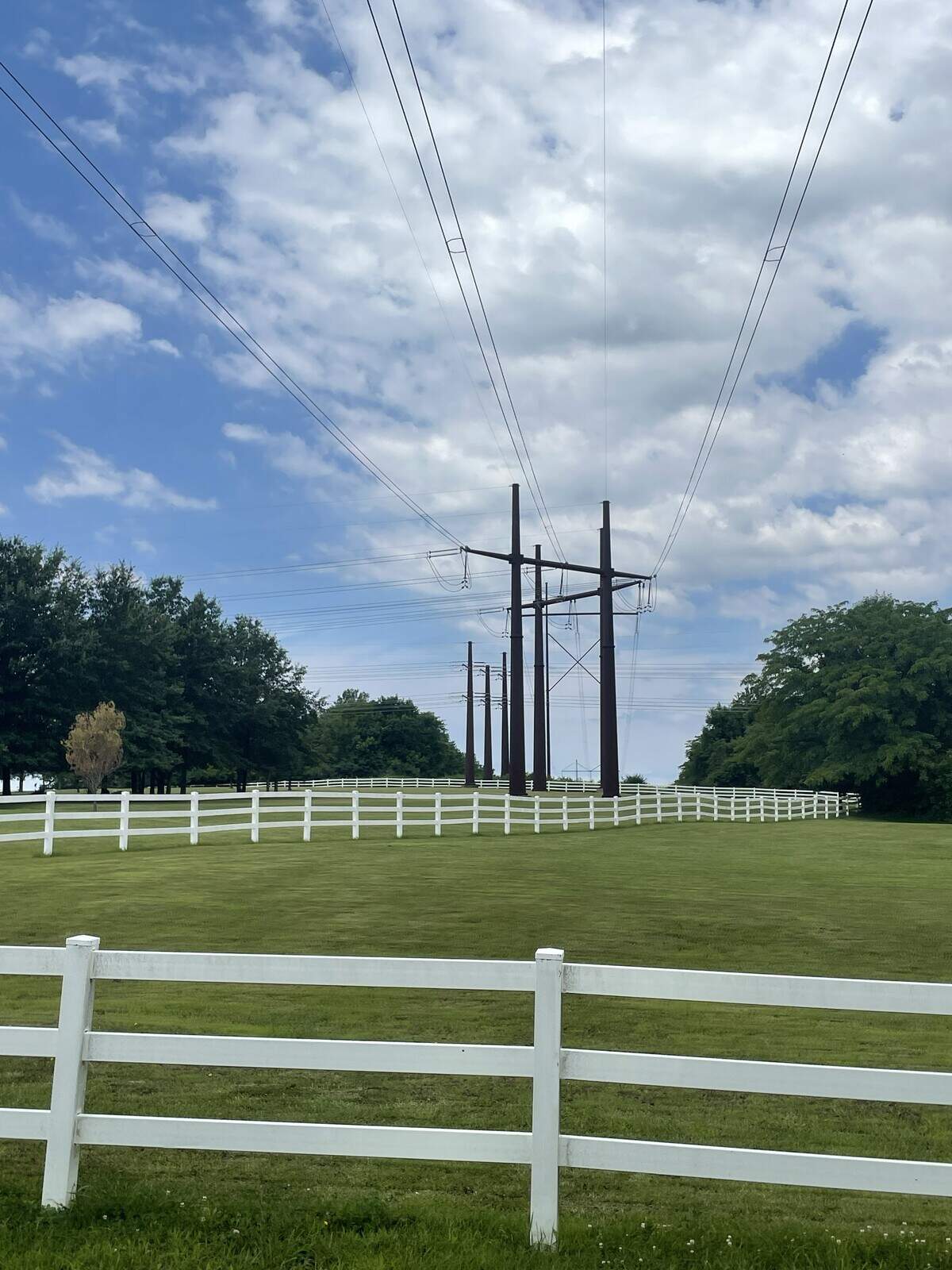Large power lines cut through the Grand Oaks Farms neighborhood in Peculiar, Missouri, on the morning of June 16, 2026.