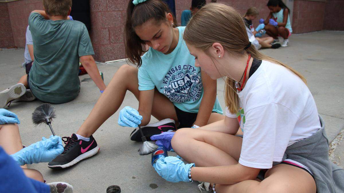 Gabby Nichols, 13, and Rosalyn Leven, 13, work together to dust a soda can for fingerprints at the Lee’s summit Junior Police Academy.
