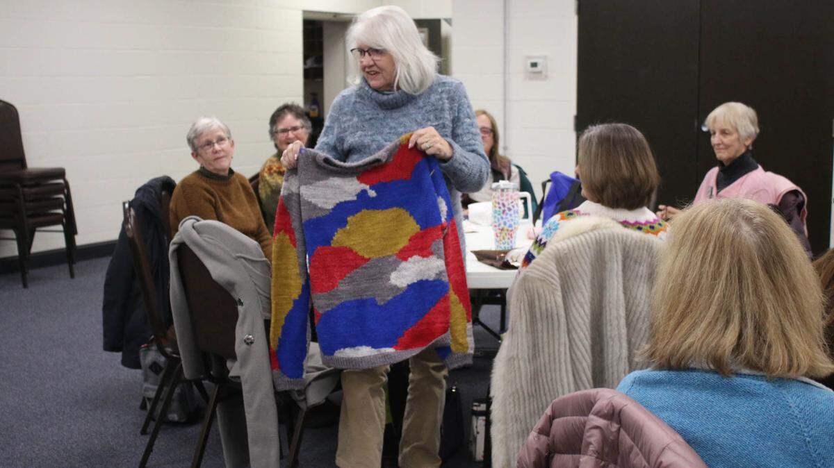 Sharon DeHaemers of Merriam shows fellow Sunflower Knitters members a sweater she made for a family member who requested Chiefs and Royals colors.