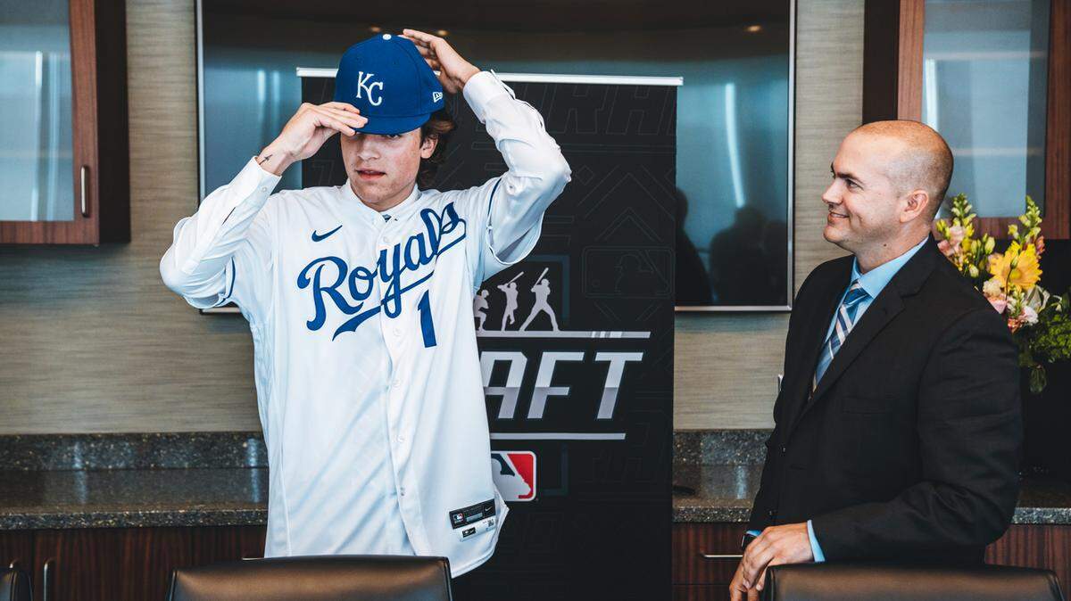 Kansas City Royals 2021 first round draft pick Frank Mozzicato puts on a Royals jersey and baseball cap alongside area scout Casey Fahy after having signed his contract at Kauffman Stadium on Saturday July 17, 2021, in Kansas City, Mo.