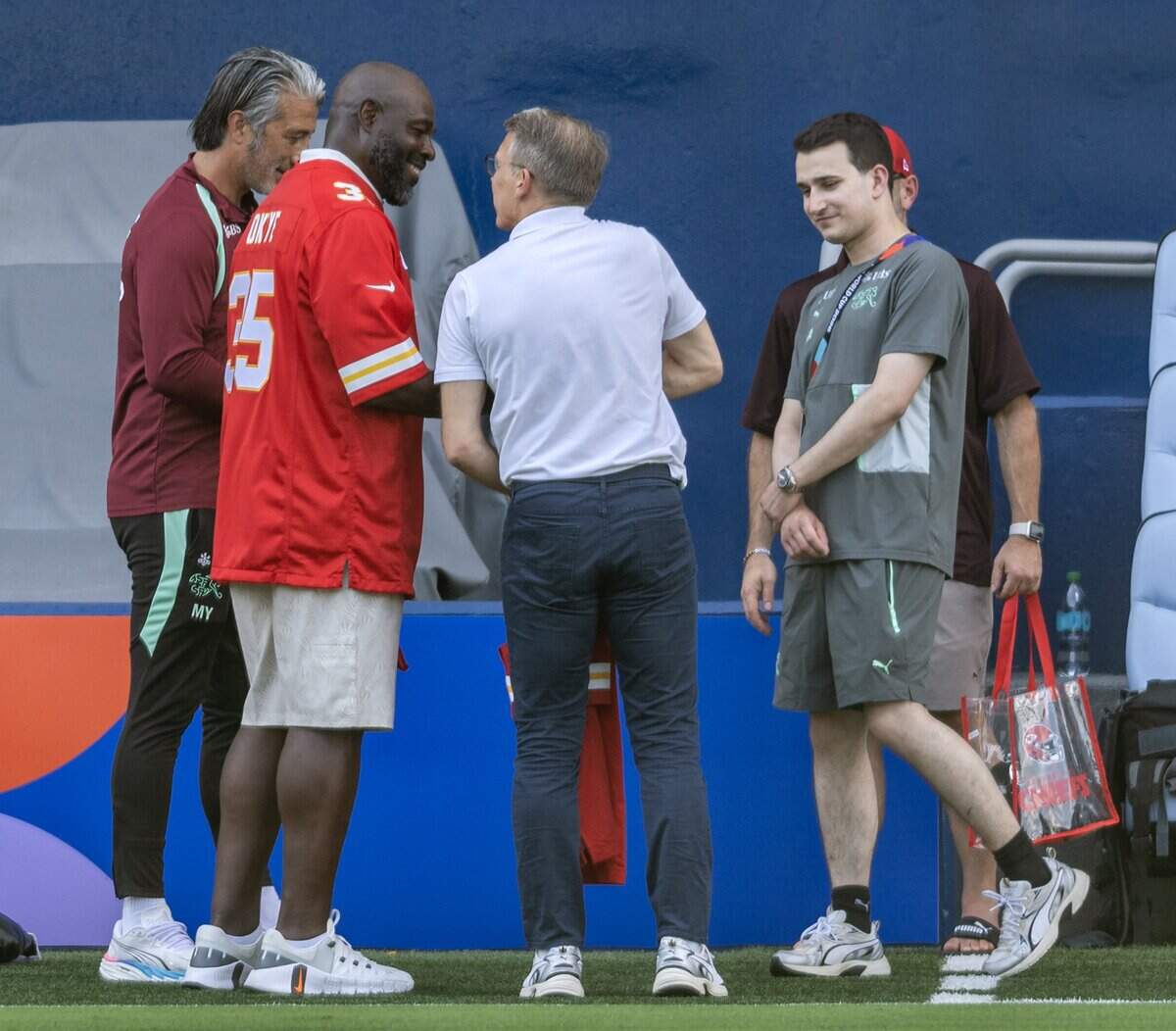 Former Kansas City Chiefs fullback Christian Okoye, left, presents a Chiefs jersey to members of the Switzerland national soccer team during practice at Sporting Park on Thursday, July 9, 2026, in Kansas City, Kansas.