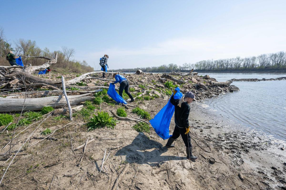 Volunteers fill bags of trash from the banks of the Missouri River during Saturday’s cleanup event.