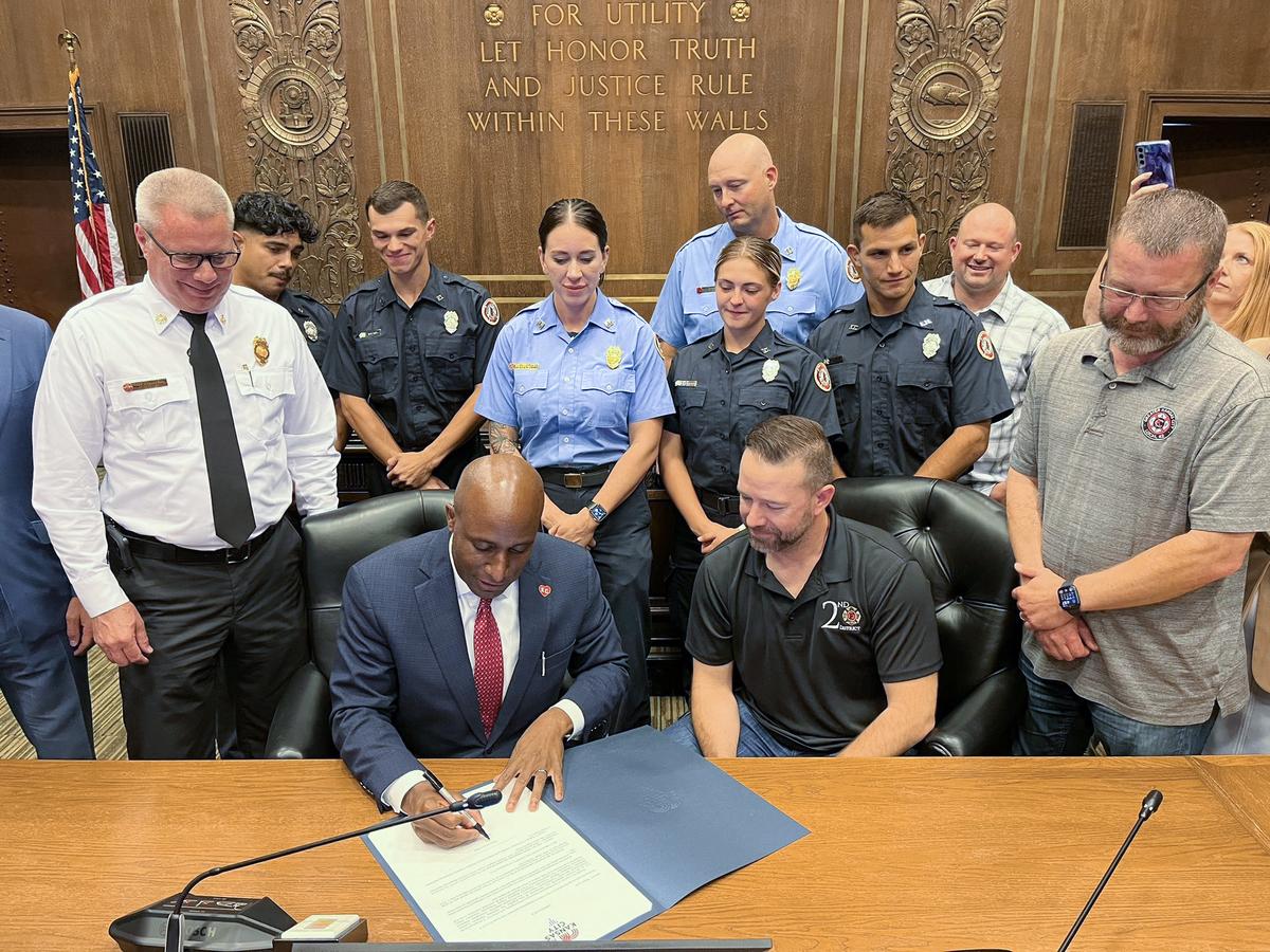Kansas City Fire Chief Ross Grundyson, left, looks on as Mayor Quinton Lucas celebrates the approval of a new five-year labor contract with members of Local 42 of the International Association of Fire Fighters in August.