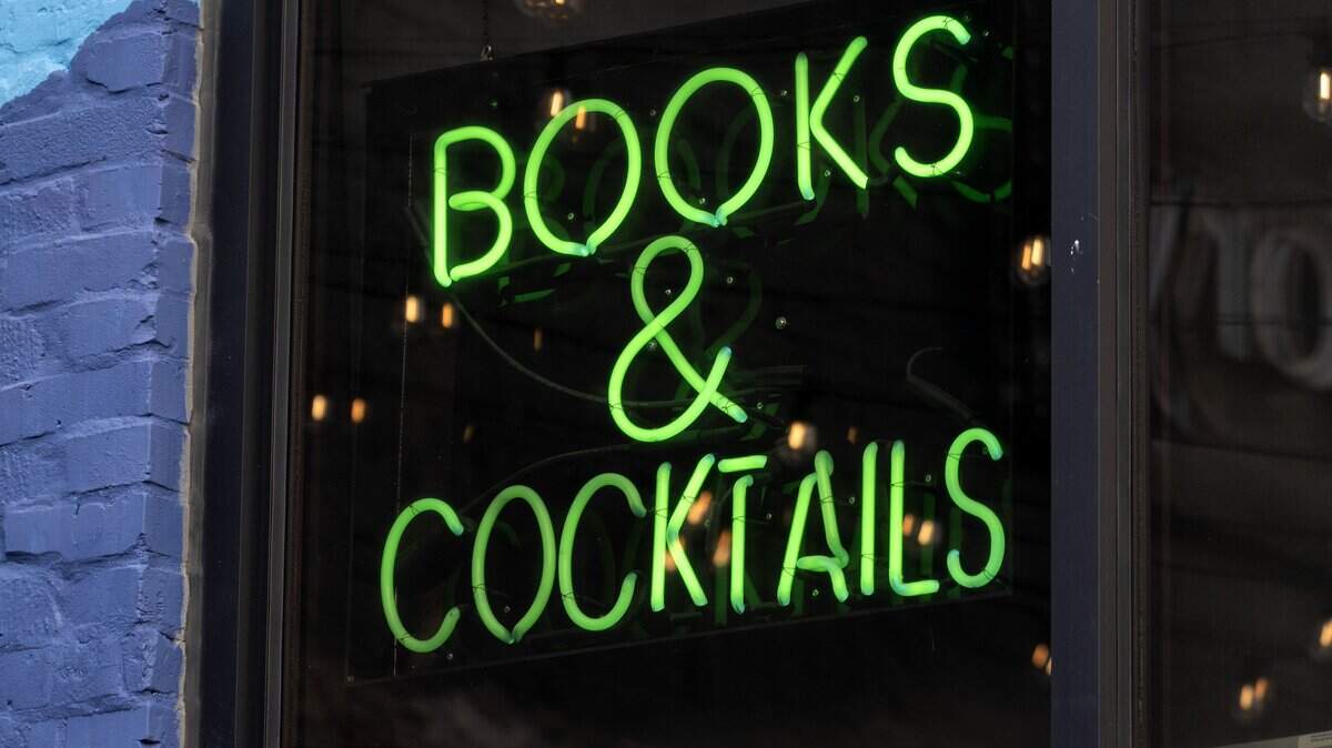 A neon sign reading “Books & Cocktails” is displayed at the back entrance of Afterword on Wednesday, Dec. 3, 2025, in Kansas City.