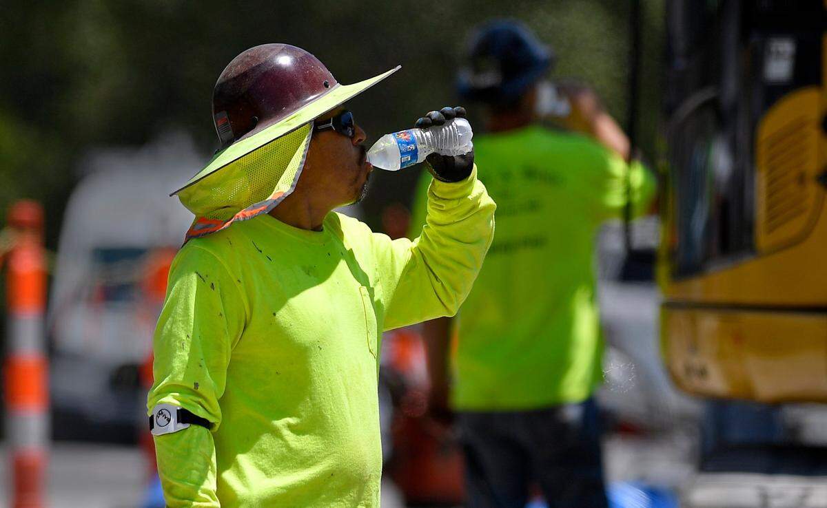 FILE PHOTO. A construction worker drinks water while working on installing new water lines in Kansas City.