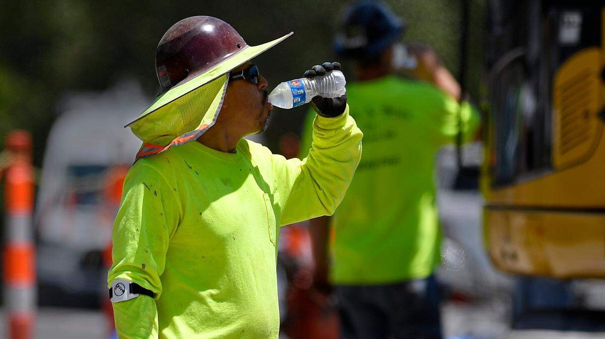 FILE PHOTO. A construction worker drinks water while working on installing new water lines in Kansas City.