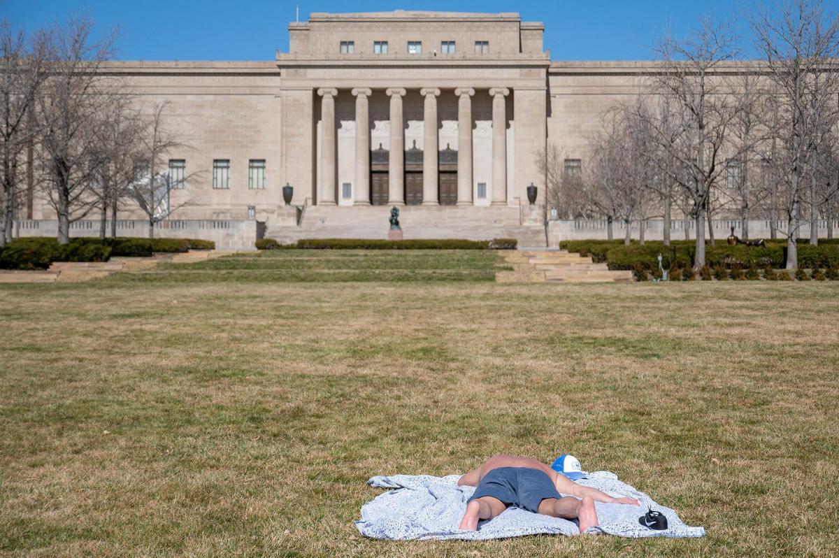 A visitor sunbathes on the front lawn of The Nelson-Atkins Museum of Art on Tuesday in Kansas City.