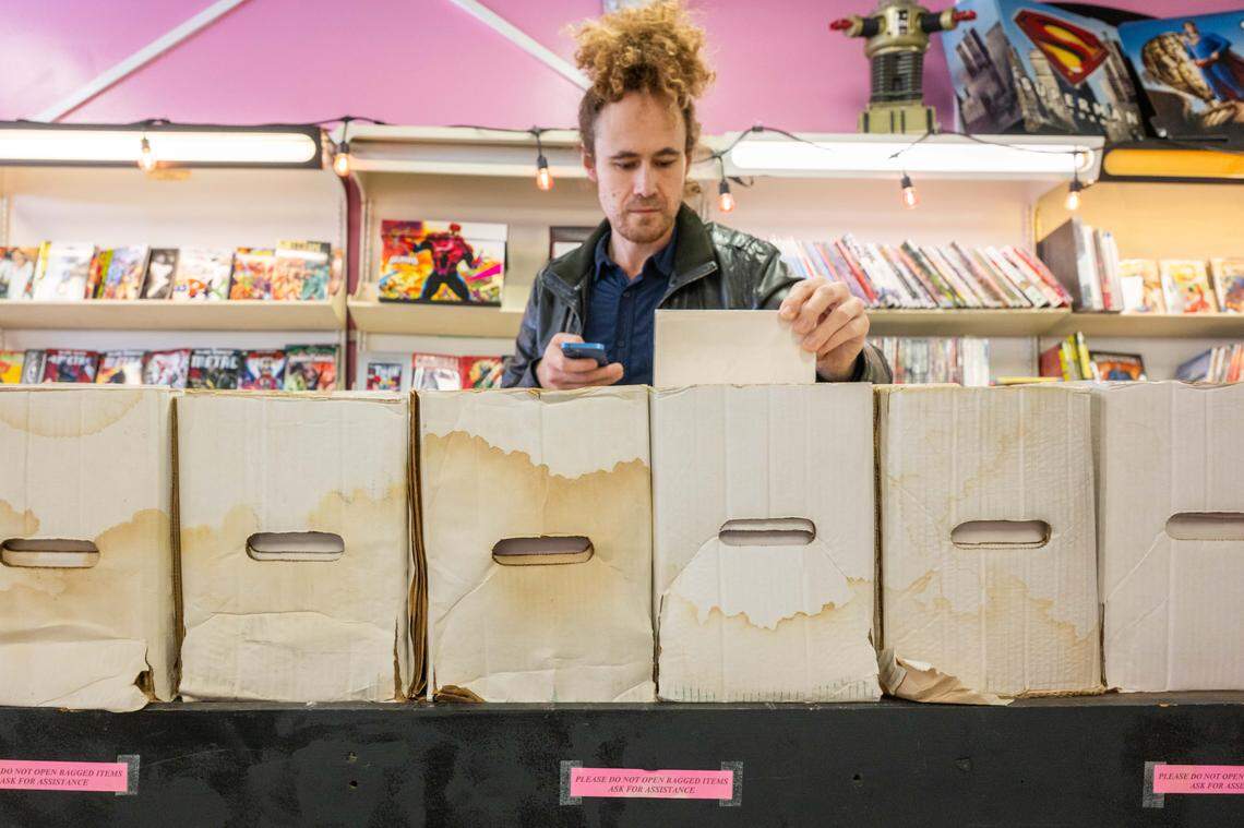 Sam Kreamer browses for comics in water damaged boxes at the new location of Clint's Comics in Independence on Tuesday, January 7, 2026. Clint's Comics was previously located in Midtown Kansas City before the roof collapsed on the building it occupied.