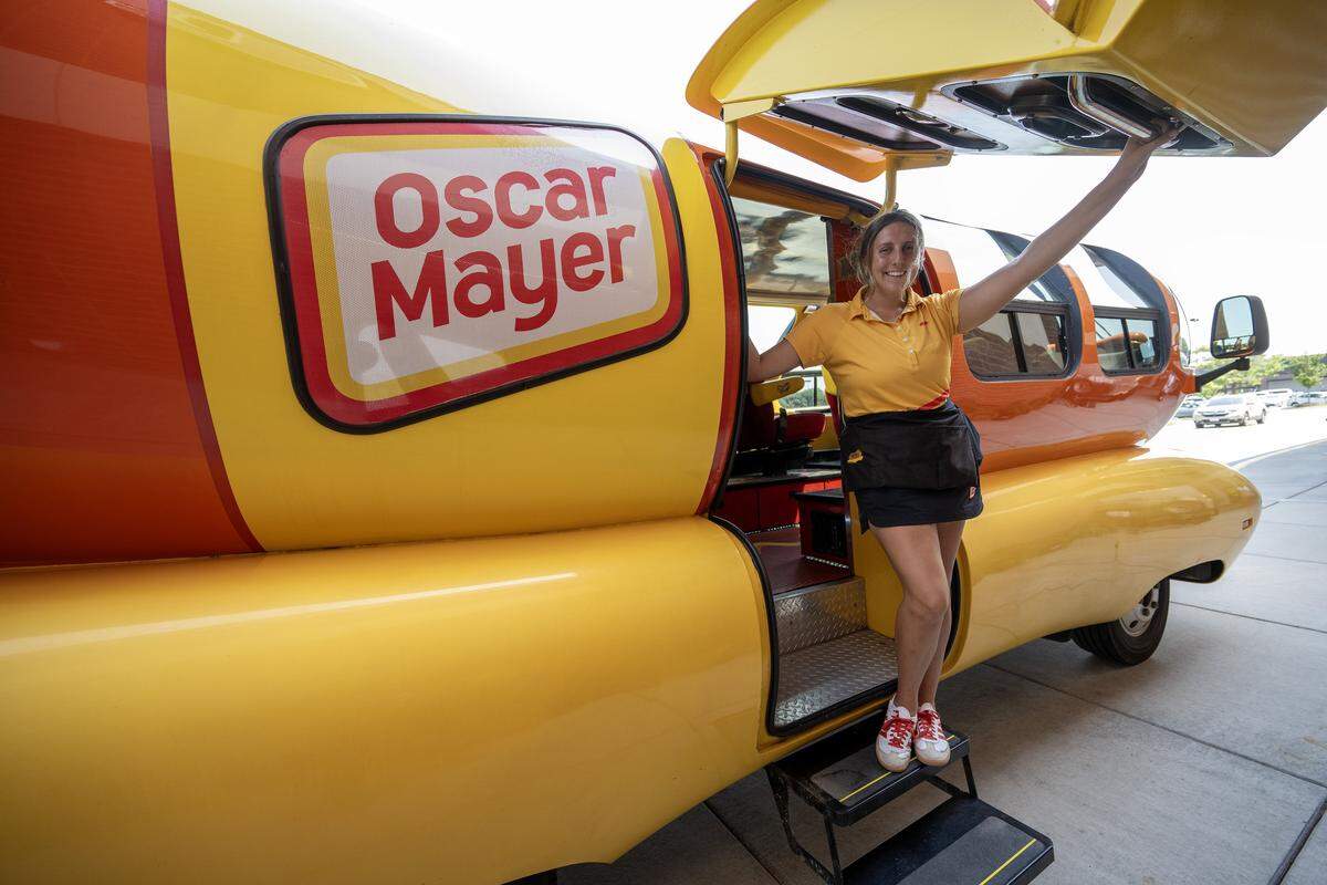 Oscar Mayer Hotdogger Reana Sinclair, known as RelishRaena, stands for a portrait beside the Wienermobile as it visits a local Hy-Vee on Friday, Aug. 8, 2025, in Lee's Summit.