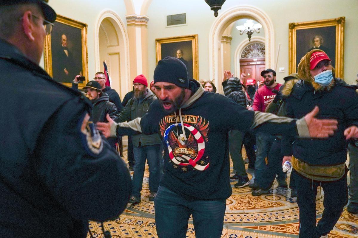 Trump supporters gesture to U.S. Capitol Police in the hallway outside of the Senate chamber at the Capitol in Washington, Wednesday, Jan. 6, 2021. (AP Photo/Manuel Balce Ceneta)