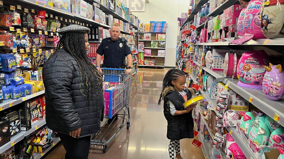 Noah McKinnis, 7, walks with her mom, Spencer Johnson, 31, and Officer Kurt Dunn, in the toy aisle for the Olathe Police Department’s annual, “Mission Christmas Event.”