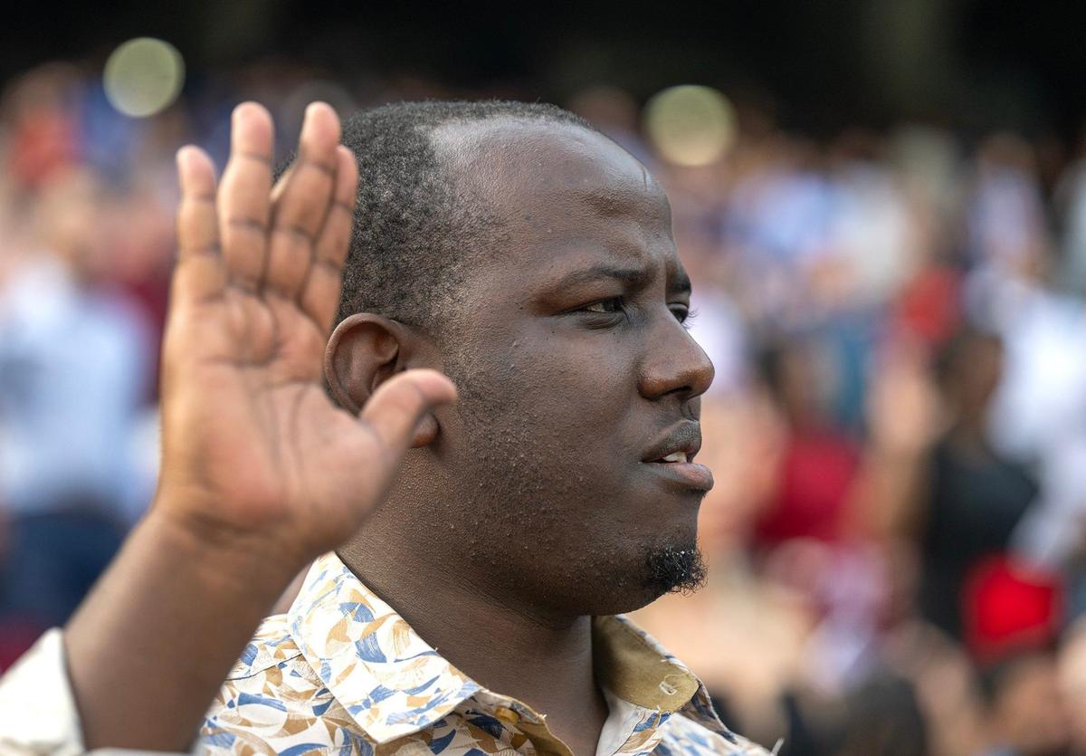 Obed Byishimo, left, a native of Democratic Republic of the Congo, takes the Oath of Allegiance Thursday at Kauffman Stadium. Byishimo is a student living in Columbia, Missouri.