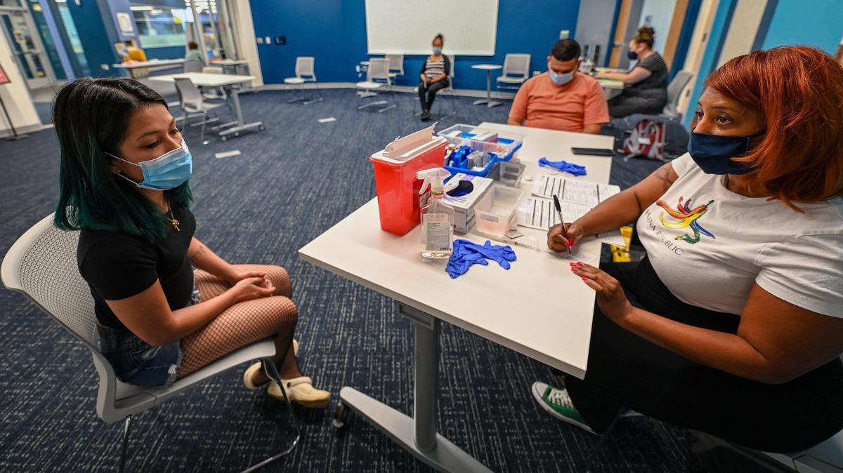 Yency Fuentes Mejia was checked in for a COVID-19 vaccination by Talisha Johnson at a KC CARE Health Center clinic Thursday at the Northeast branch of the Kansas City Public Library.