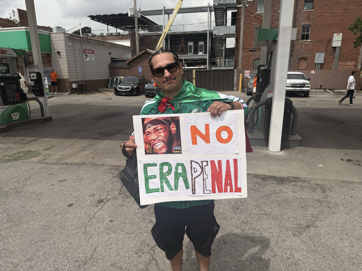Kansas City firefighter paramedic Fidel Cervantes holds a “No Era Penal” sign at the Dutch soccer “Orange Walk” parade through downtown Kansas City on Thursday, June 25, 2026.