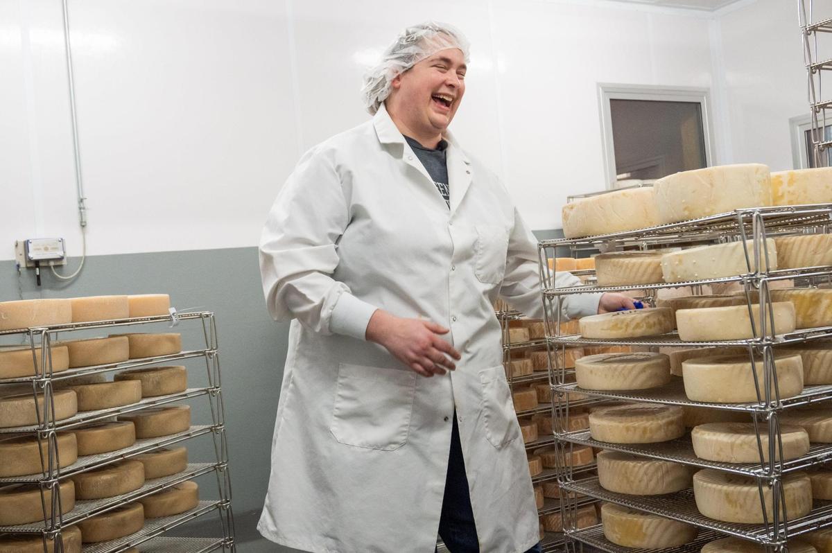Helen Cowan, Director of Dairy Operations at Green Dirt Farm, stands amongst hundreds of wheels of Prairie Tomme, their in-house, aged sheep’s milk cheese at Green Dirt on Oak in Kansas City.